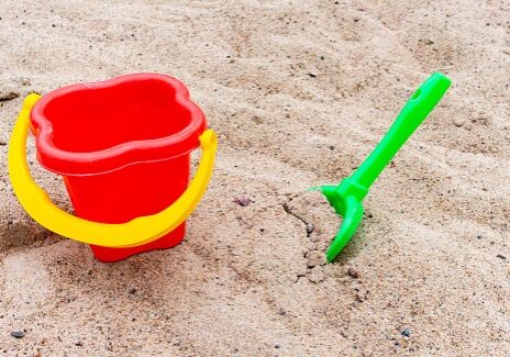 Bright children's red bucket and a green scoop on a sandbox Bright children's red bucket and a green scoop on a sandbox.